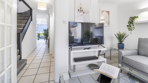 Un soggiorno moderno con una TV a schermo piatto, un tavolino in vetro e un divano grigio.