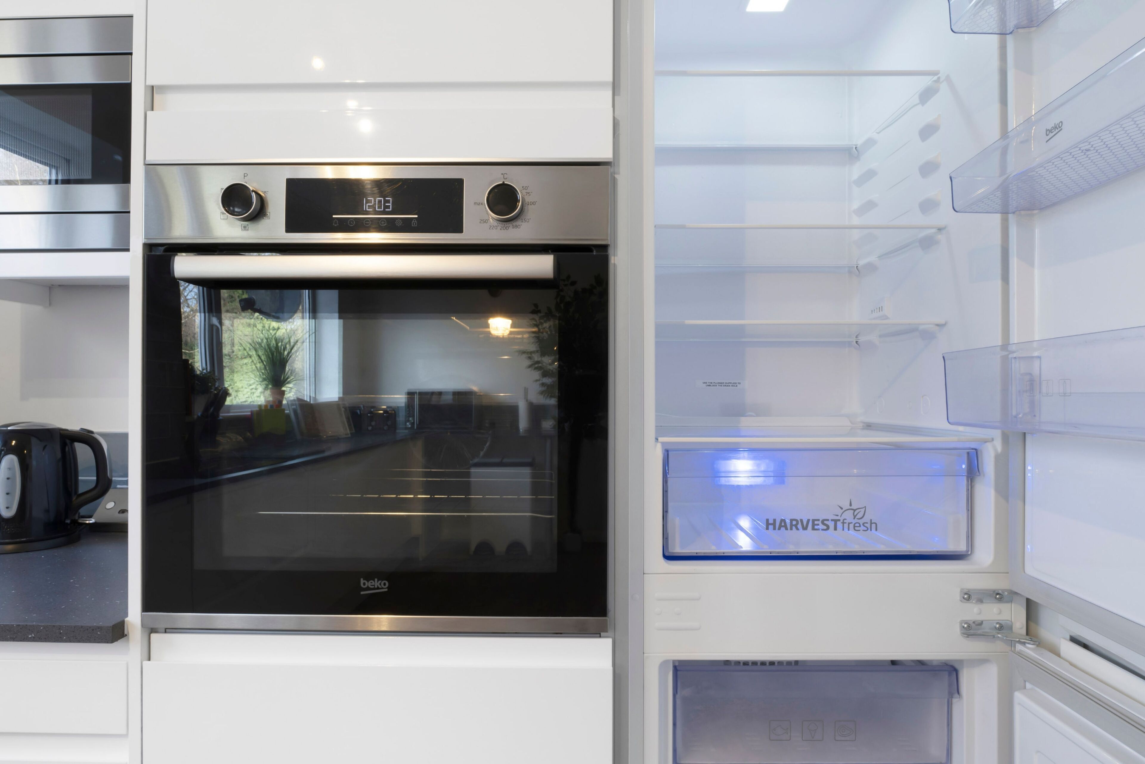 Una cocina con horno integrado y refrigerador con etiqueta 'HARVESTfresh'.