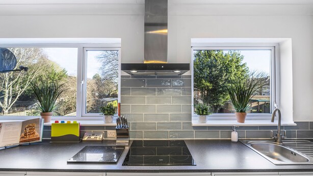 Una cucina moderna con piano cottura nero, lavello in acciaio inossidabile e una grande finestra.