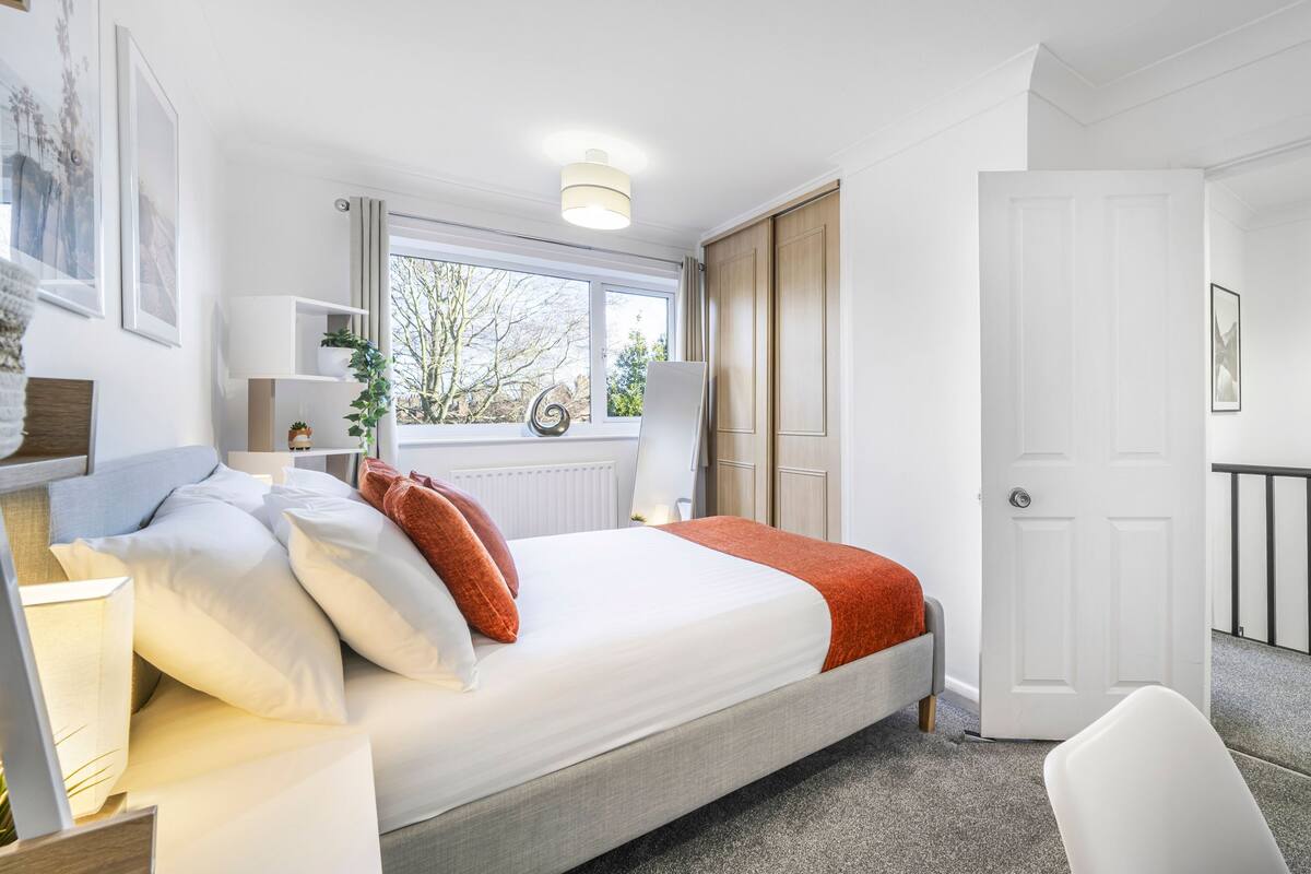 A neatly arranged bedroom with a bed, bedside tables, a window, and a door.
