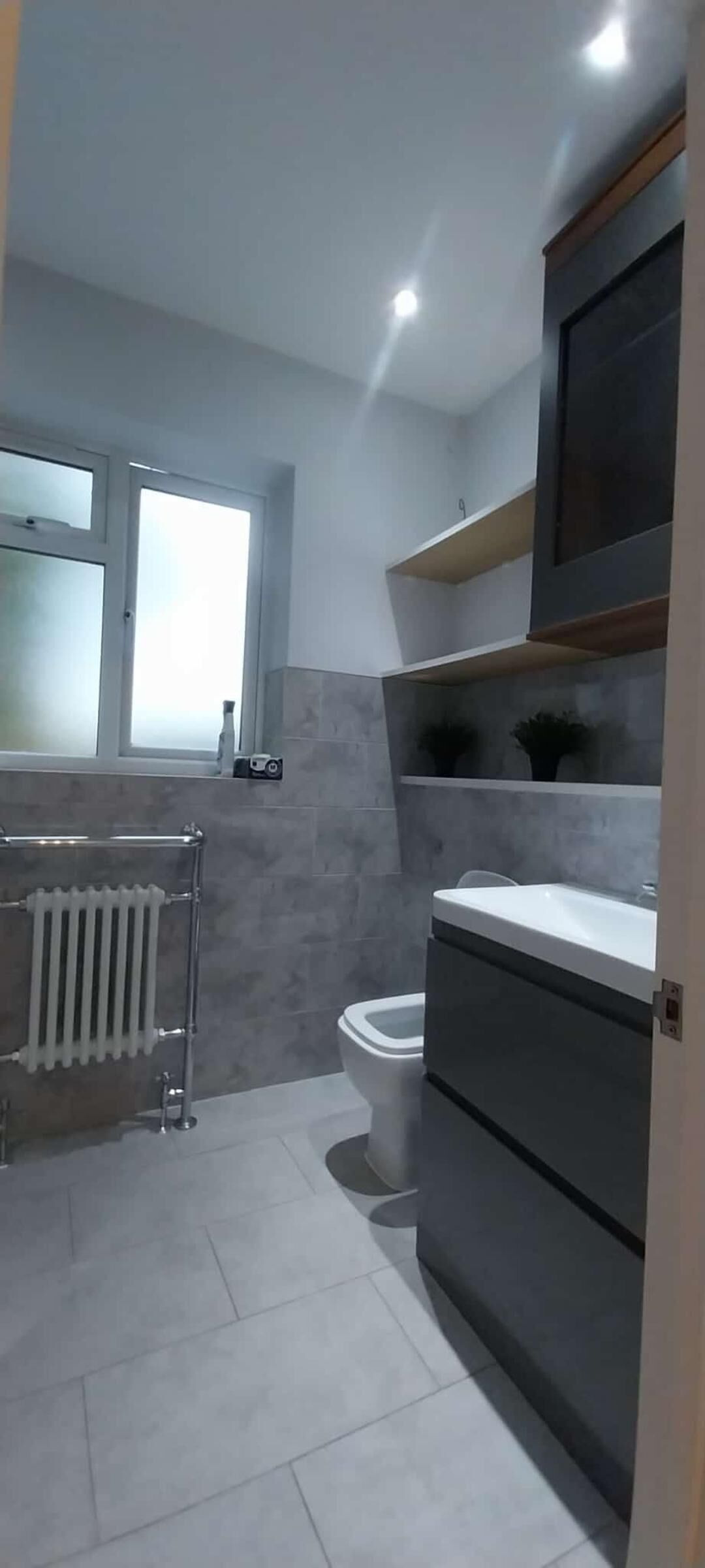 A modern bathroom with a toilet, a radiator, and a sink.
