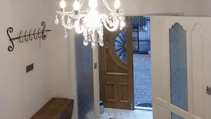 Un couloir orné d’un lustre, avec un banc en bois et une porte donnant sur l’extérieur.