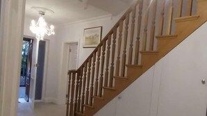 Un hall d’entrée spacieux, doté d’un escalier en bois et d’un lustre.