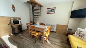 A cozy room with a dining table, chairs, a sofa, a TV, a radiator, and a wooden shelf with a microwave. - Cozy vacation home surrounded by nature, pets allowed. (San Giacomo Filippo)