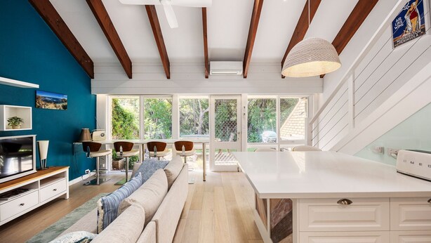 A modern kitchen with a large island, wooden beams, and a view of the outdoors. - Pet Friendly - Captain Sandy on the Loop Blairgowrie (Blairgowrie)