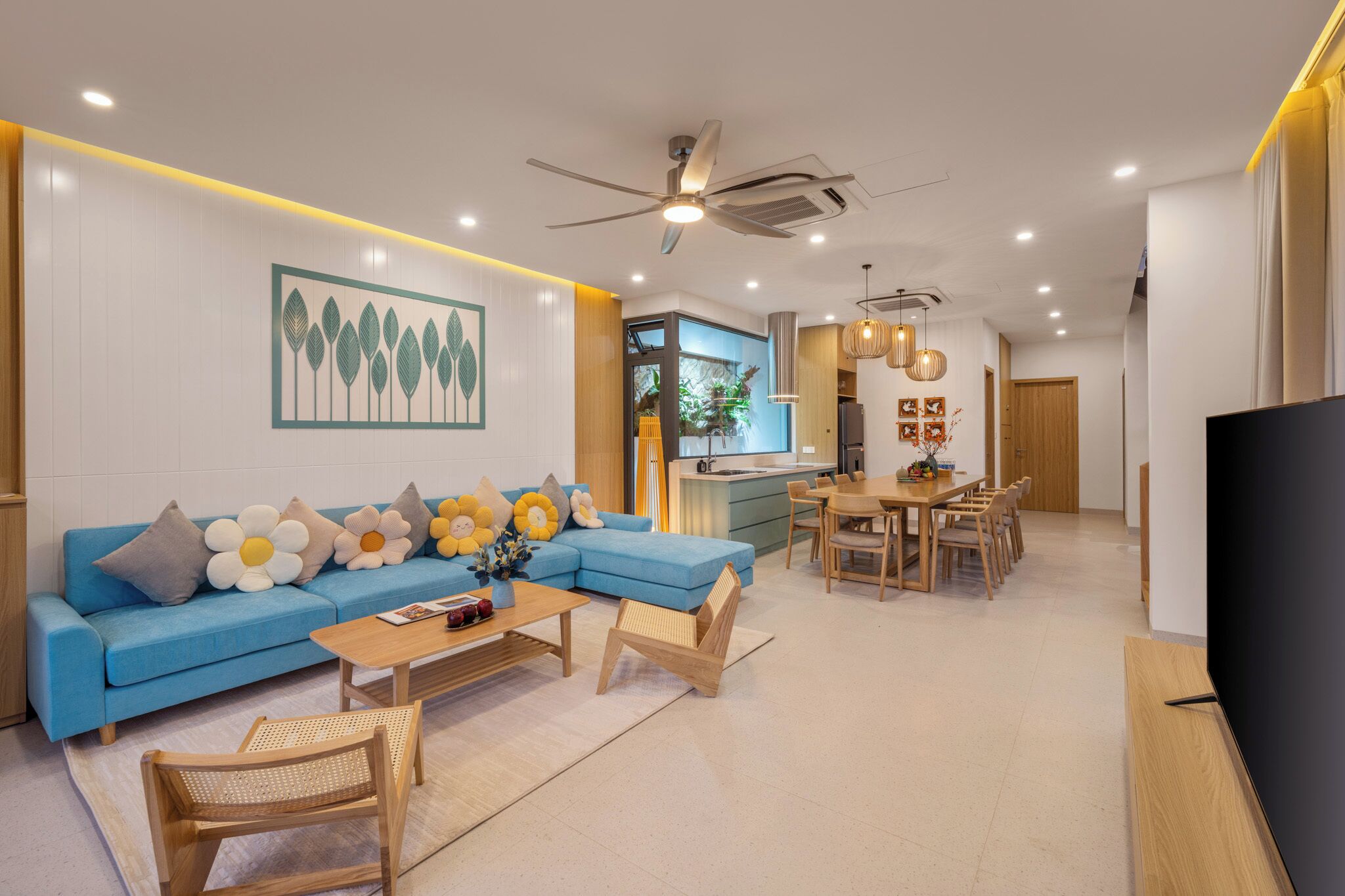 Una sala de estar moderna con un sofá azul, una mesa de centro de madera y un televisor.
