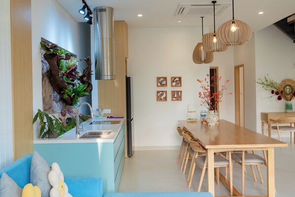 A modern kitchen with a central island, stainless steel appliances, and a dining area with wooden furniture. - Kim Son Pool Villa Da Nang (Da Nang)