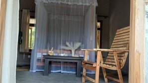 Une pièce avec un plafond en bois, un lit à baldaquin, une chaise en bois et une table ornée d’un vase et d’objets décoratifs.
