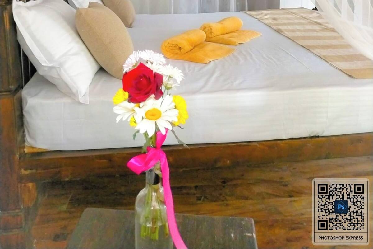 Una cama con dosel, almohadas, un ramo de flores y toallas sobre la cama.