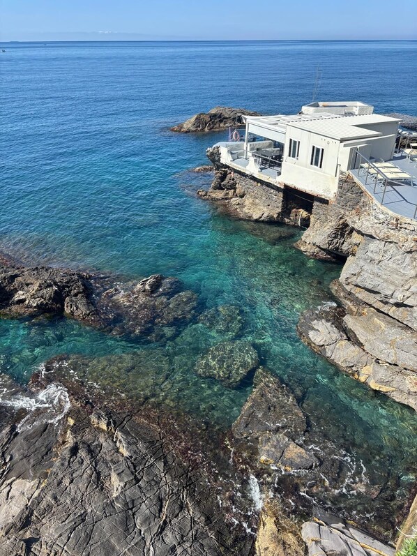 Un bâtiment situé sur la côte, doté d’un balcon donnant sur la mer et construit sur un terrain rocheux.