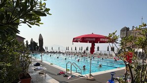 A swimming pool with multiple lanes, lifeguard umbrellas, and lounge chairs.