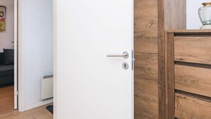 Eine weiße Tür mit silberner Klinke, ein Holzschrank mit Schubladen und ein Heizkörper am Boden.