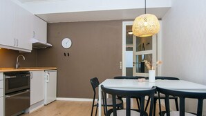 Eine moderne Küche mit integrierten Geräten, ein Essbereich mit rundem Tisch und Stühlen sowie ein großes Fenster mit Blick.
