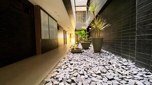 A corridor with a tiled floor, potted plants, and a modern interior design. - Flat FM20 Cabo Branco L6 - By Almare (João Pessoa)