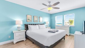 A bedroom with a bed, nightstands, a ceiling fan, and a window with blinds. - Life's A Beach - Pet Friendly, Private Pool, Beach Views, Across from Beach! (St George Island)