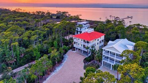 Une propriété située sur la côte, avec un bâtiment à toit rouge, entourée d’une végétation luxuriante et offrant une vue sur la mer.