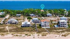Un quartier résidentiel situé sur la côte, avec des propriétés donnant sur la plage, notamment des maisons dotées de balcons et d’une piscine.