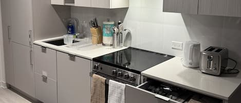 Equipped with a sink, coffee maker, and toaster, this kitchen offers ample storage and a clean aesthetic.