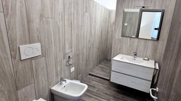 A modern bathroom with a bidet, a sink, a mirror, and a toilet.