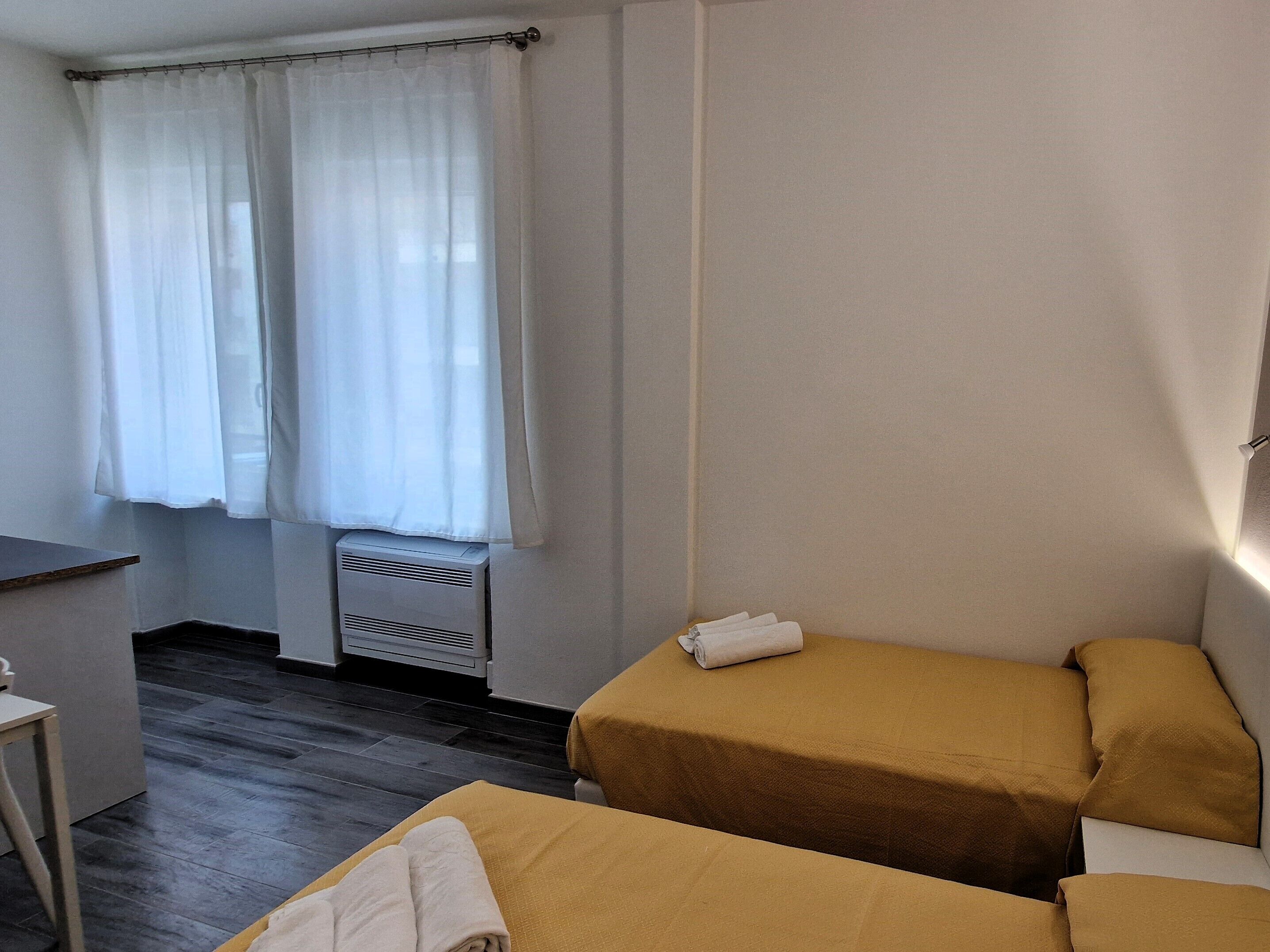 A room with two beds, a desk, and a window with curtains.