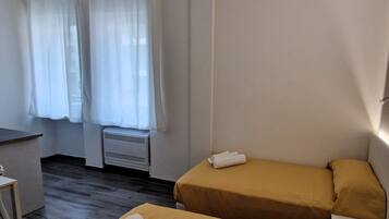 A room with two beds, a desk, and a window with curtains.