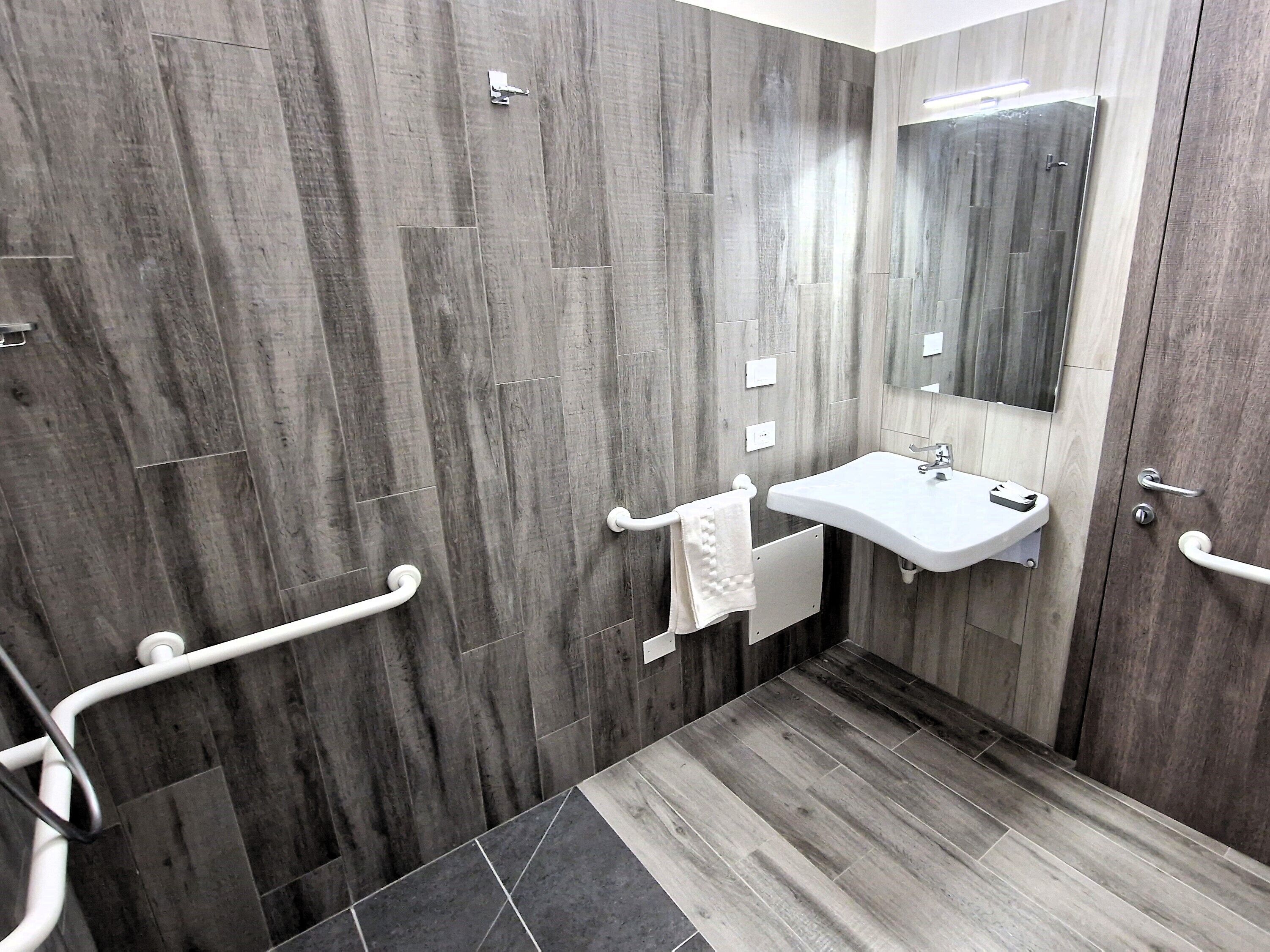 Un baño moderno con suelo de madera, un lavamanos blanco y un espejo.