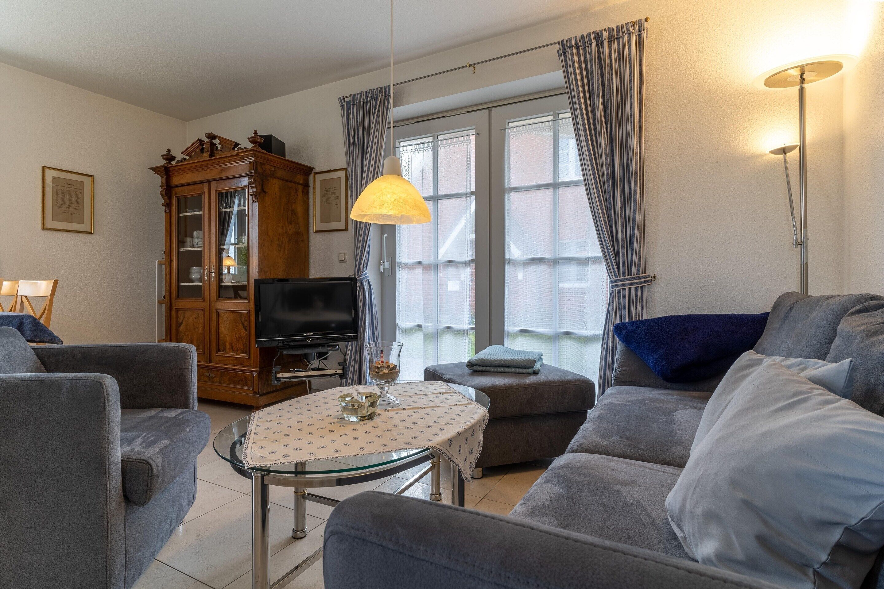 A living room with a sofa, armchair, and a small table with a lamp.
