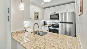 A modern kitchen with granite countertops, stainless steel appliances, and pendant lighting.