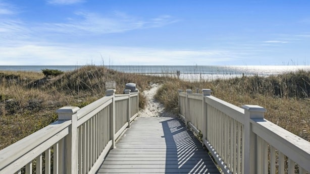 A wooden boardwalk leading to a beach with a clear sky.