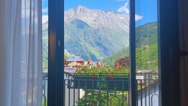 A mountain view from a balcony with a railing, a mountain, and some buildings in the background.