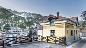 A yellow building with a chimney, a wooden fence, and a mountain backdrop.