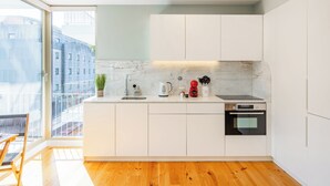 Eine moderne Küche mit weißen Schränken, einer Marmor-Spritzschutzleiste, einem eingebauten Backofen und einem großen Fenster mit Blick auf eine Stadtlandschaft.