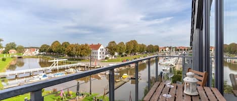 Een balkon met uitzicht op een rivier, boten en huizen.