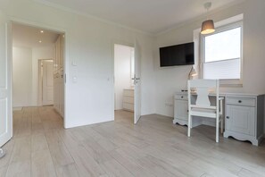 Ein Zimmer mit Schreibtisch, Stuhl und Fernseher an der Wand.