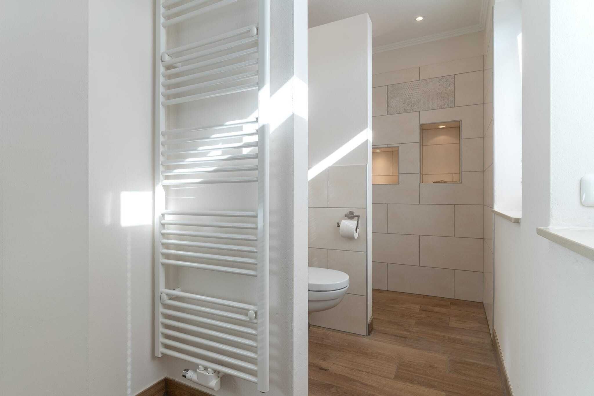 A modern bathroom with a toilet, a towel rack, and a wooden floor.