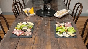A wooden dining table with two black slate boards, each holding an assortment of cheeses, meats, and vegetables. - Our establishment is located not far from Clermont-Ferrand in the charming littl (Saint-Saturnin)