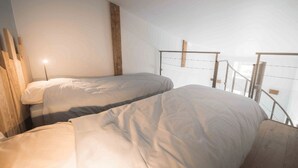 A room with two beds, a wooden beam, and a metal railing. - Our establishment is located not far from Clermont-Ferrand in the charming littl (Saint-Saturnin)