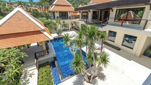 A modern resort with a central swimming pool, multiple villas with red-tiled roofs, and lush greenery. - Naiharn 4br Private PoolVilla near Beach (Rawai)