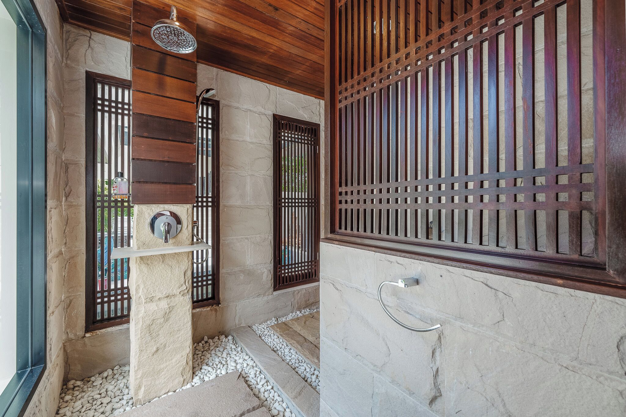 A bathroom with a stone wall, a wooden ceiling, and a metal faucet.