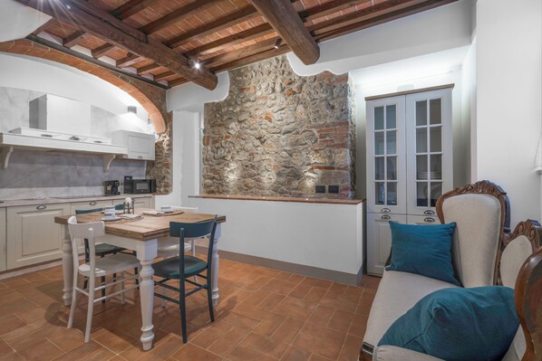 Una cocina con armarios blancos, una pared de piedra y techo de madera.