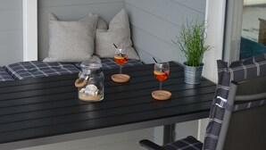 A corner seating area with a black table, two grey pillows, a glass jar with a rope handle, two glasses with drinks, and a small potted plant. - Houseboat Hecht with spacious roof terrace in Schleswig (Schleswig)