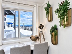 Een kamer met een groot raam, een statieflamp en meerdere wandplanten.
