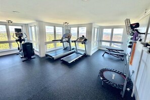 Een sportschool met loopbanden, een hometrainer en een trampoline.
