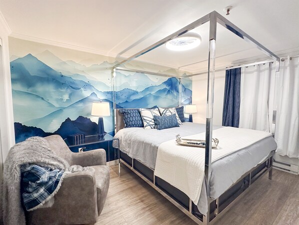 Een hemelbed met een bergdecoratie, een stoel met een plaid en een nachtkastje met lampen.