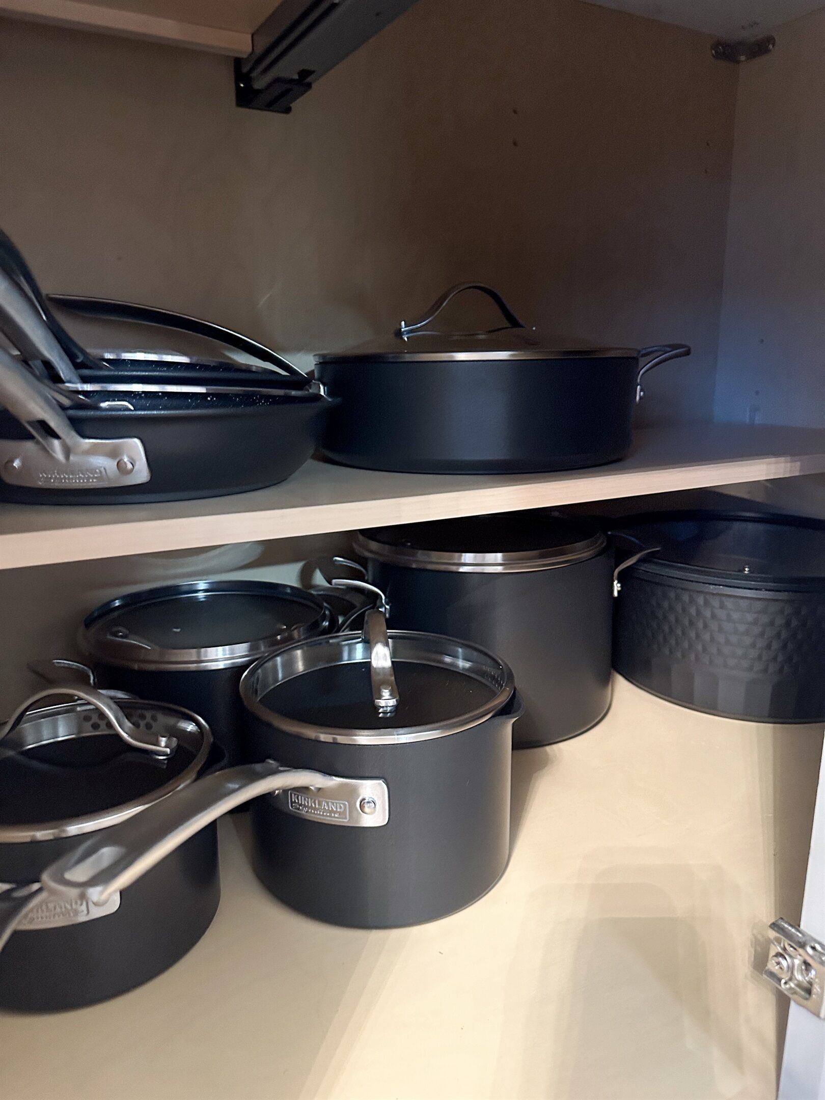 A kitchen with black cookware on shelves.