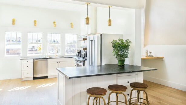 A modern kitchen with white cabinetry, stainless steel appliances, and a central island with stools. - Sherman Lodge (Kalispell)