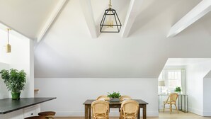 A dining area with a wooden table, four wicker chairs, and a black hanging light fixture. - Sherman Lodge (Kalispell)