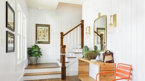 A staircase with wooden steps and a wooden handrail, leading to a landing with a wooden console table, a mirror, and a potted plant. - Sherman Lodge (Kalispell)