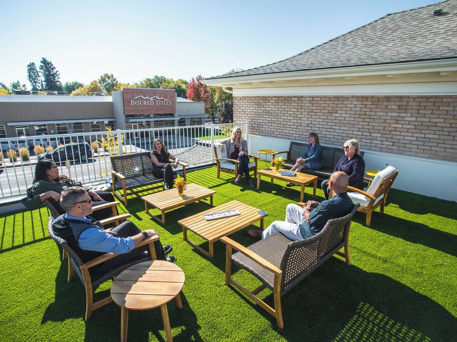 A rooftop patio with outdoor seating, a brick building, and a sign for 'Insured Titles'.