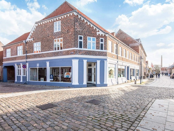 A brick building with a blue facade, large windows, and a cobblestone street.